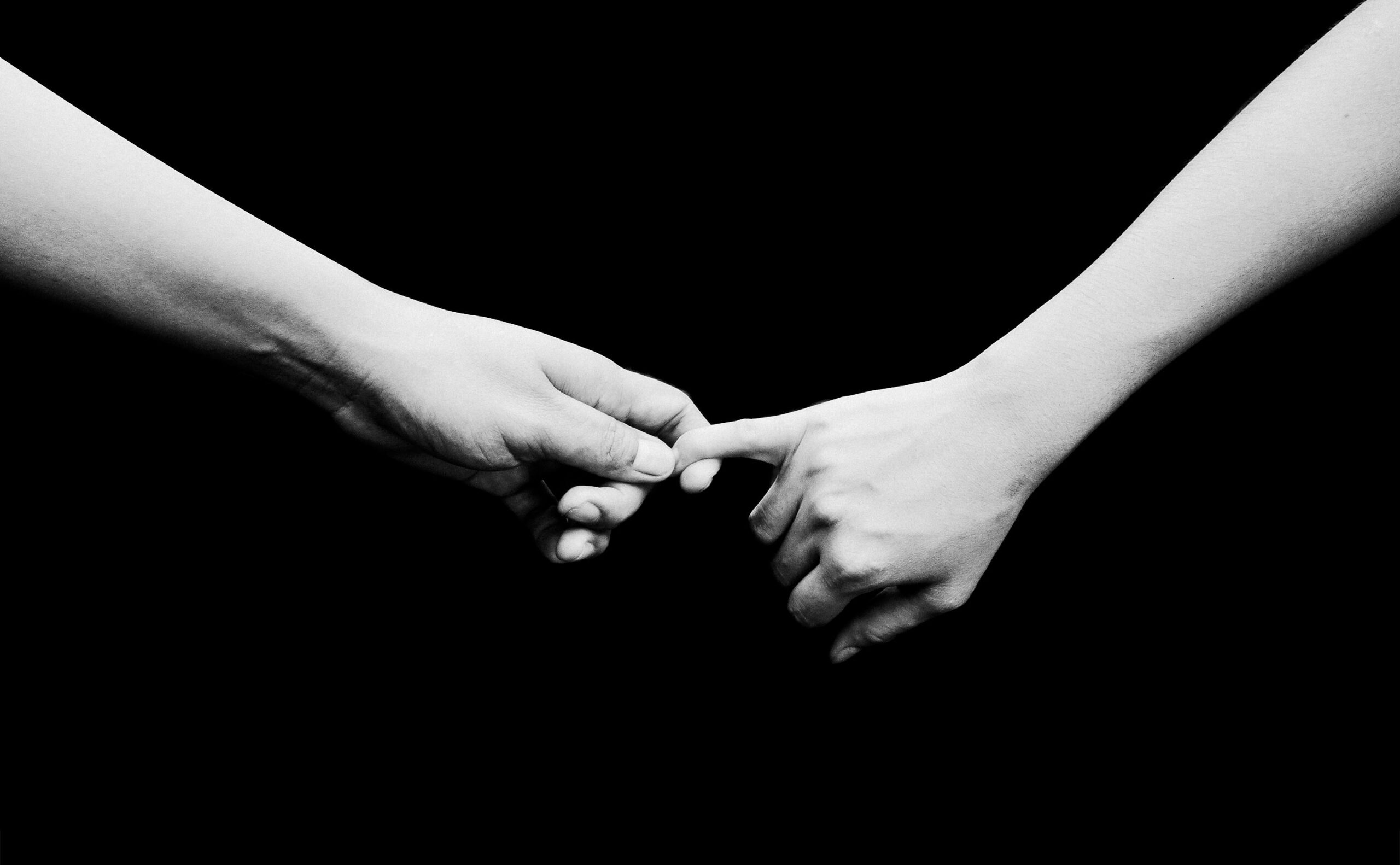 Two hands reaching out in a black and white composition, symbolizing connection.